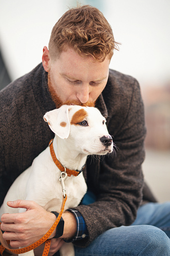 Handsome young man spending time with his dog walking outdoors in the city