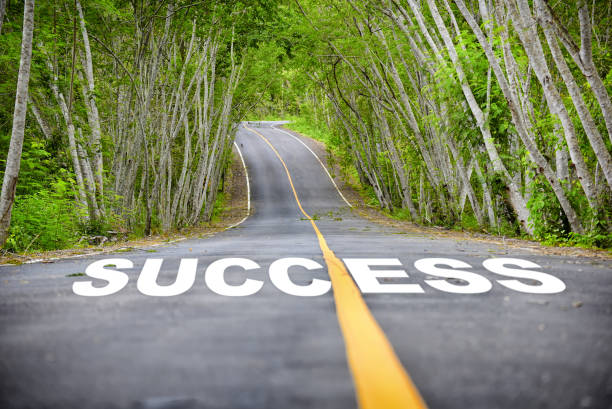 Tree tunnel with success word on asphalt road surface stock photo