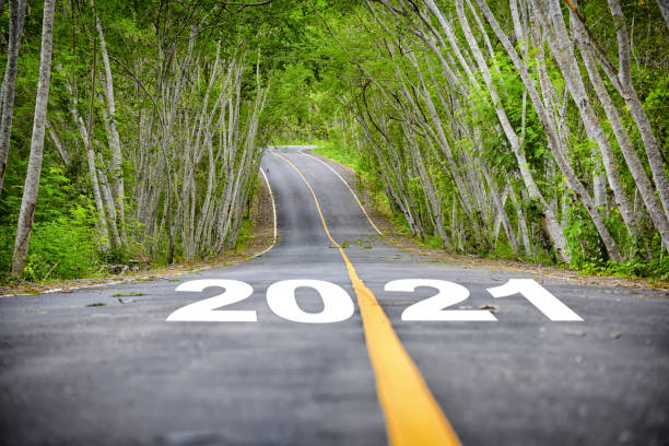 Tree tunnel with number 2021 on asphalt road surface