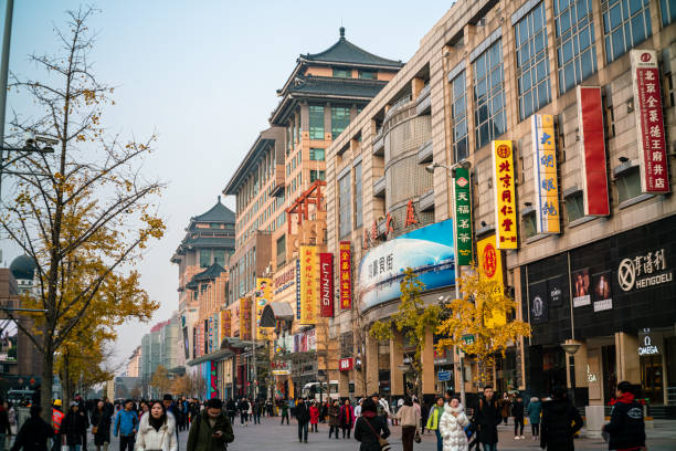 Wangfujing Shopping Street, Beijing, China Beijing, China-November 23, 2019: People walk on Wangfujing Street, the most famous shopping street in Beijing, with nearly 300 shops and shopping centers. This is a popular place for locals and tourists around the world. The tree-lined pedestrian area is home to shops, ranging from high-end designers to everyday consumer goods stores. wangfujing stock pictures, royalty-free photos & images