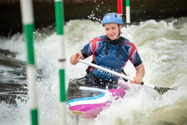 Close up of a happy GB Canoe Slalom Athlete negotiating the poles of slalom gates on white water in the C1W class.