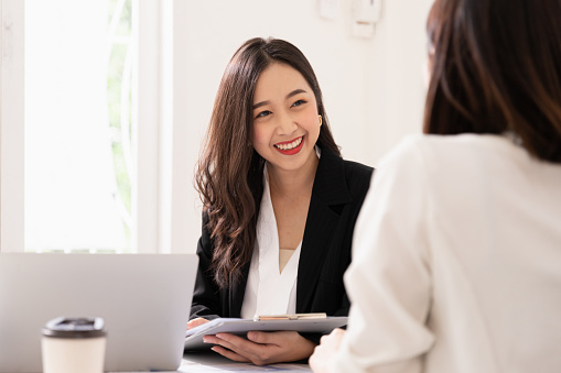 Una joven atractiva mujer asiática está entrevistando para un trabajo. Sus entrevistadores son diversos. Gerente de recursos humanos realizando entrevista de trabajo con los solicitantes en la oficina photo