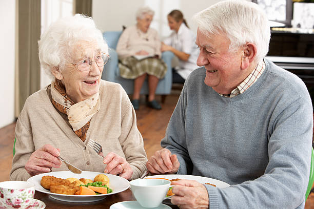 sorridente casal idoso a comer refeições no tratamento inicial - senior adult nursing home eating home interior imagens e fotografias de stock
