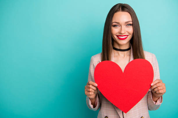 close-up portrait of nice attractive lovely charming cute cheerful cheery straight-haired girl holding in hands big heart symbol isolated on bright vivid shine vibrant blue green turquoise color background - valentines day short necklace necklace brown hair stock-fotos und bilder