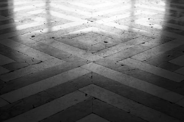 Old style shiny stone mosaic floor tiling with geometric pattern, black and white background photo texture