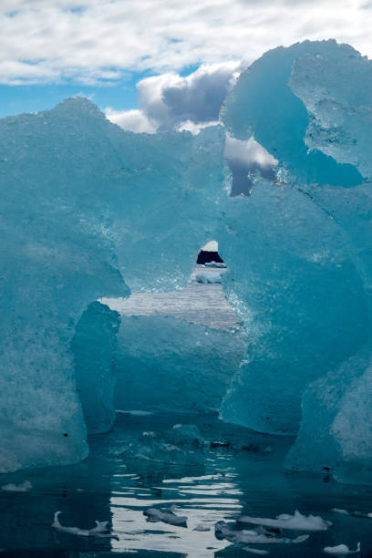A scenic view of a blue coloured iceberg floating off of the coast of the Antarctic peninsula.