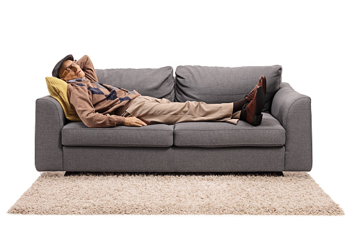 Elderly man sleeping on a sofa isolated on white background