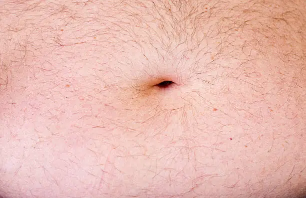 Overweight man's tummy with hairs and belly button.