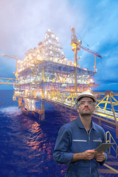 istock Caucasian man engineer staff worker with tablet in hand and offshore rig background concept. 1207277727