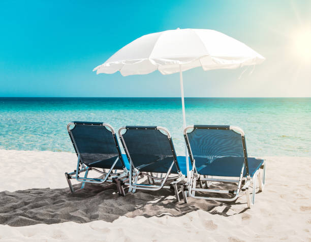 istock Three blue beach chairs bathing in the sun on a beach 1207278038