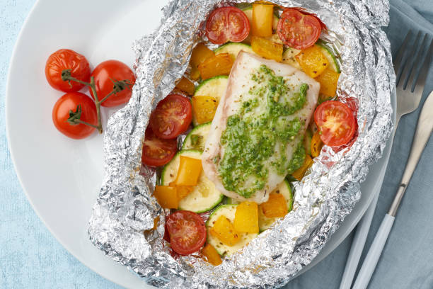 istock Foil pack dinner with white fish. Oven baked fillet of cod, pike perch with vegetables 1207278235
