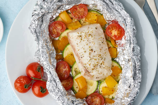 istock Foil pack dinner with white fish. Oven baked fillet of cod, pike perch with vegetables 1207278595
