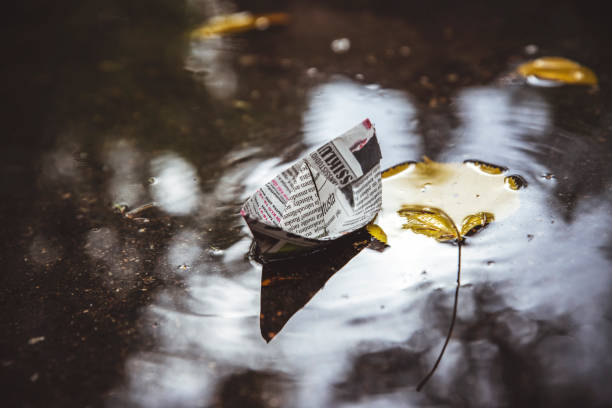 paper boat in a pool with leaves. autumn blurred toned photo for your design.autumn background