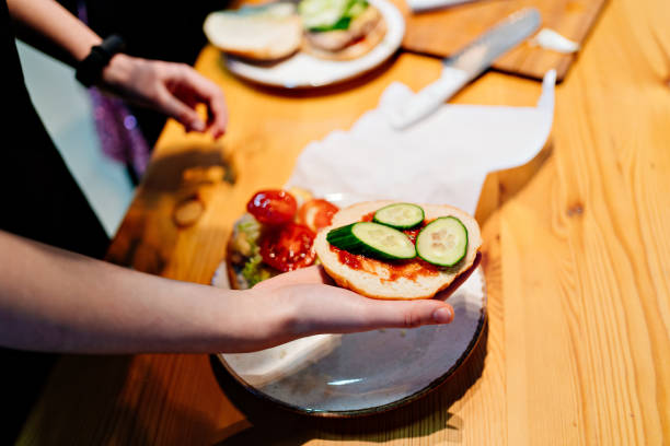 istock cook Burger. bread with ketchup and cucumber hand 1207280114