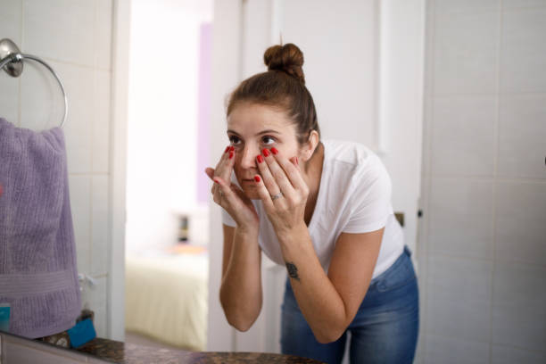 young woman doing skin care at bathroom - hair bun hairstyle beautiful looking imagens e fotografias de stock