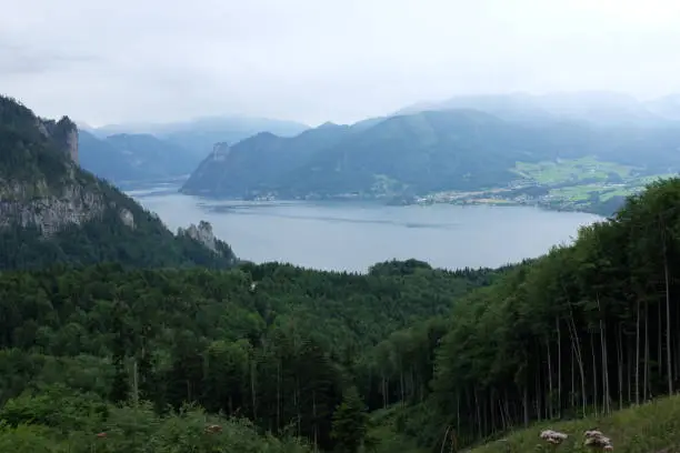 July 27, 2017 - Saalachtal, Austria: panorama of blue tranquil lake among the mountains and fir trees with clouds very low in Austrian Alps.