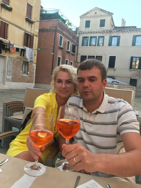 July 29, 2017 - Venice, Italy: beautiful mature couple toasting cocktail while sitting at dinner at restaurant in Venice square while on summer vacations