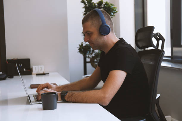 istock Man using laptop and listening to music 1207283479