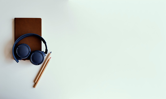 Headphones with notebook on white desk