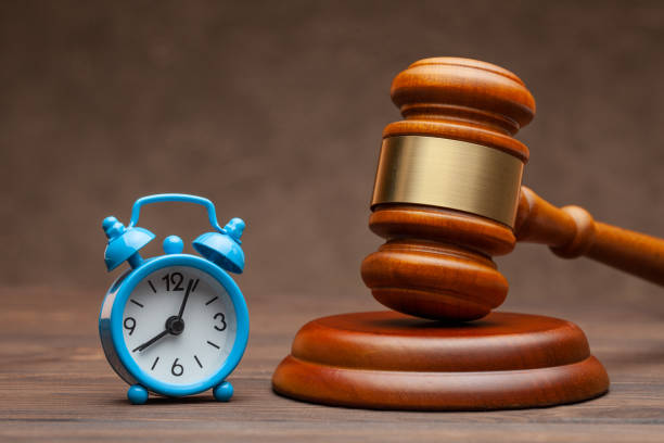 istock Alarm clock and hammer judge gavel on brown background 1207285610