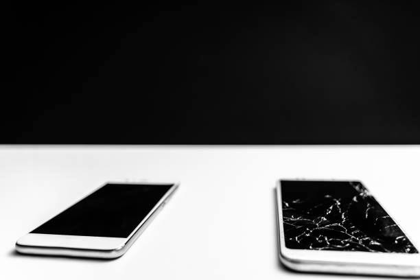 Two white smartphones, one is with cracked screen on black background. The scene is located in a studio environment. The footage is taken with Sony A7III camera