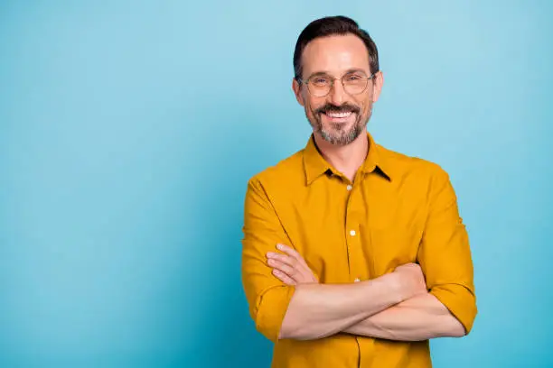 Photo of Portrait of charming mature man true boss feel content emotions wear yellow shirt isolated over blue color background