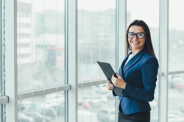 istock New minted young female analyst holding a clipboard looking at the camera, with inspired face expression. 1207288088