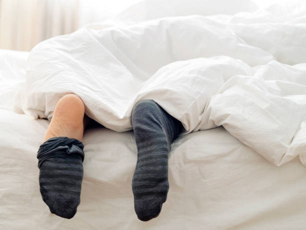 hombre perezoso quitando sus calcetines en la cama - exhaustion tired men after work fotografías e imágenes de stock