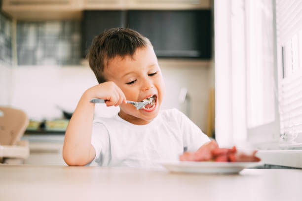 istock child in the kitchen eating sausage and mashed potatoes 1207290241