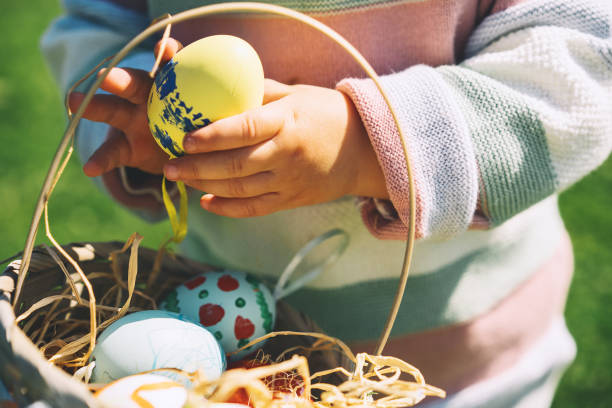 istock Colorful Easter eggs in basket. Children gathering painted decoration eggs in spring park. 1207290269
