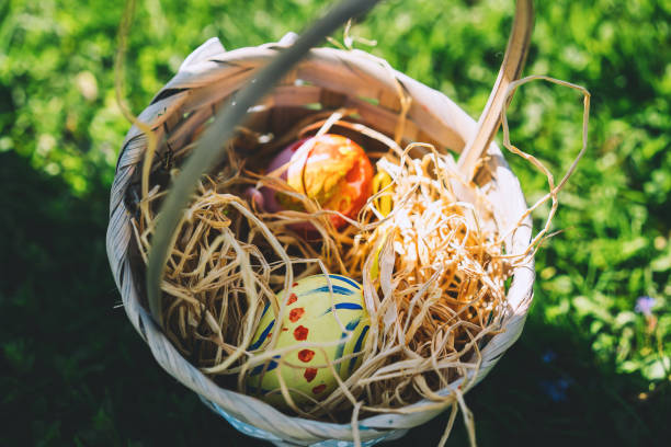 istock Painted easter eggs in wicker basket. Children gathering colorful eggs outdoors. 1207290735