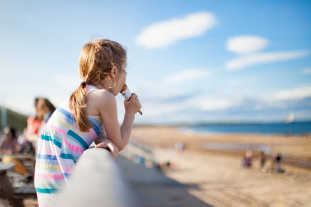 Girl eating ice-cream at the beach stock photo