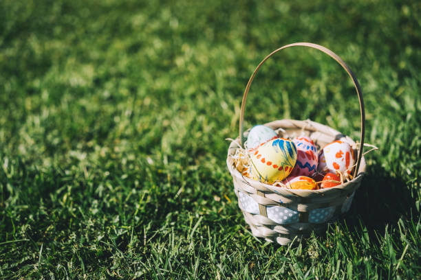 istock Painted easter eggs in wicker basket. Children gathering colorful eggs outdoors. 1207291087