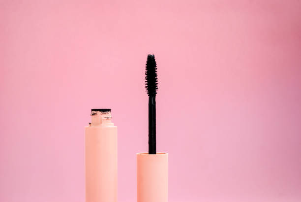 istock Black mascara with a brush in a pink bottle on a pink background. Place for text. Side view 1207291472
