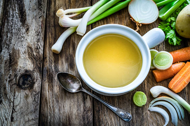 brodo di verdure con ingredienti girati sul tavolo da cucina rustico. spazio di copia - brodo foto e immagini stock