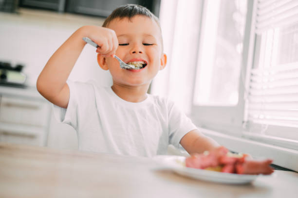 istock child in the kitchen eating sausage and mashed potatoes 1207293680