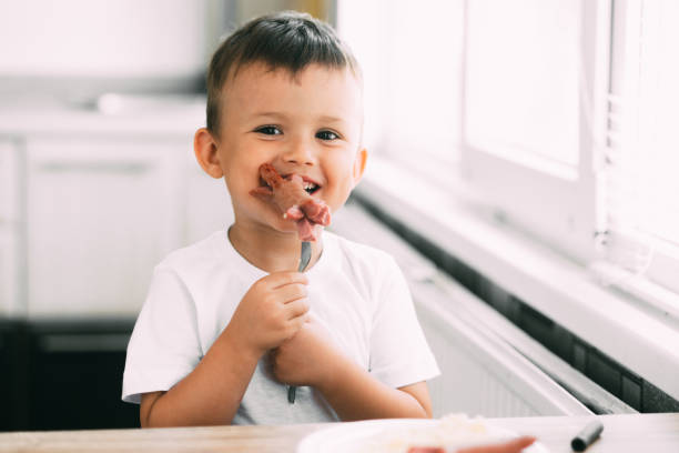 istock child in the kitchen eating sausage and mashed potatoes 1207294449