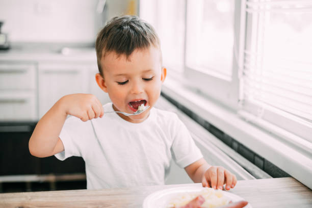 istock child in the kitchen eating sausage and mashed potatoes 1207294537