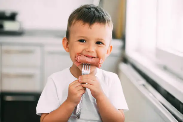 Photo of child in the kitchen eating sausage and mashed potatoes