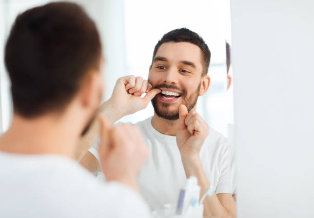 istock man with dental floss cleaning teeth at bathroom 1207296604