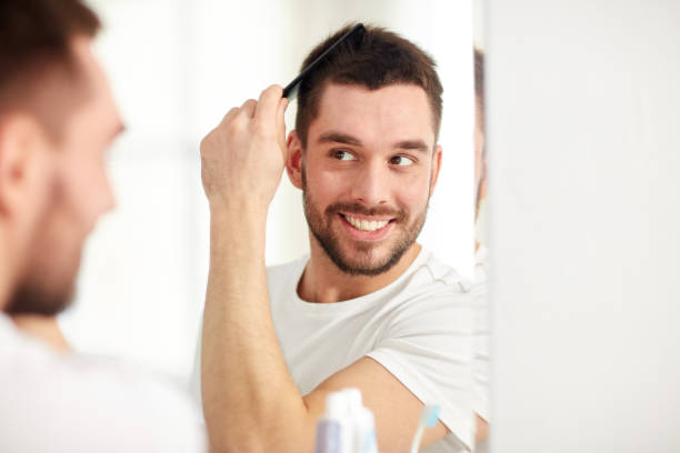 istock happy man brushing hair  with comb at bathroom 1207297134