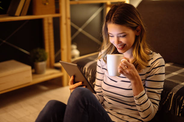 istock Young woman using digital tablet and drinking tea at night 1207298148
