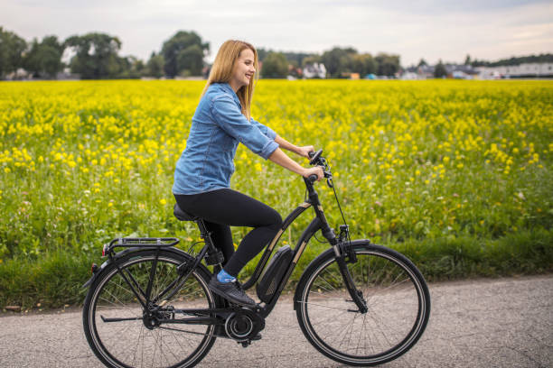 행복한 젊은 여자 승마 에 그녀의 전기 자전거 - healthy lifestyle exercise equipment exercising exploration 뉴스 사진 이미지