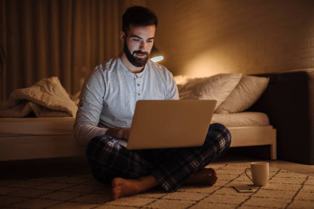 istock Young man using his laptop while sitting on the floor at home 1207298786