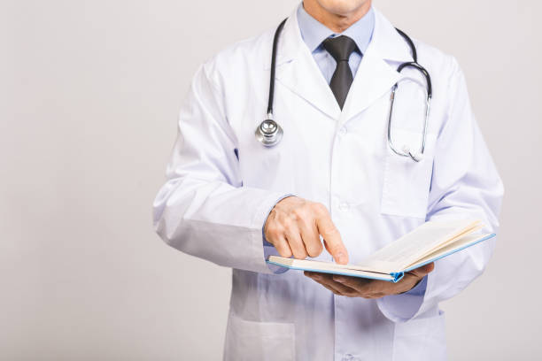 istock Senior doctor reading a book isolated over grey background. 1207299030