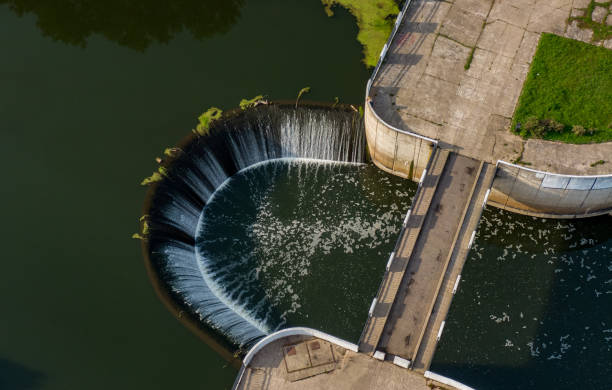 istock Funnel in the water, artificial waterfall at a hydroelectric power station, in the frame a bridge. Aerial photo, top view 1207299075