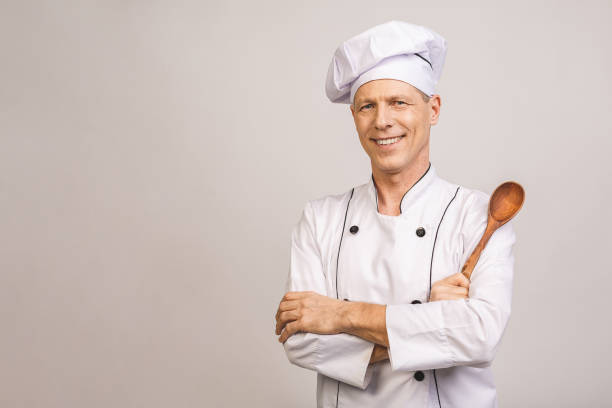 istock Smiling senior male chef isolated over white background. 1207299774