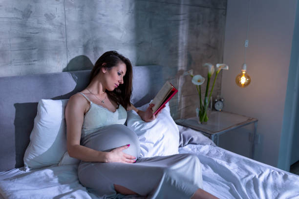 istock Pregnant woman reading in bed 1207300017