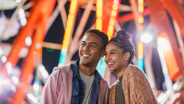 istock Young couple at county fair, by ferris wheel 1207300145