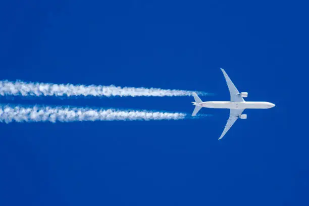 Boeing 777 in flight on blue sky and condensation trace